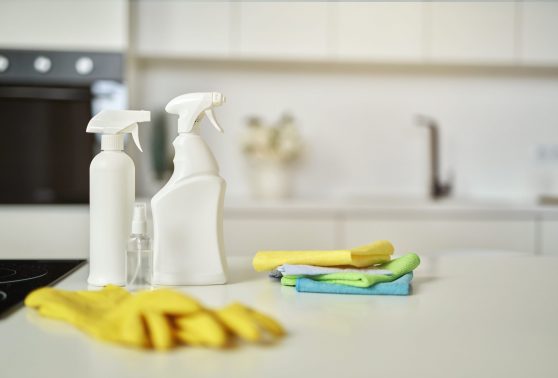 Cleaning set. Detergent bottles, stack of rugs and protective rubber gloves on surface in the kitchen. Cleaning service concept. Selective focus