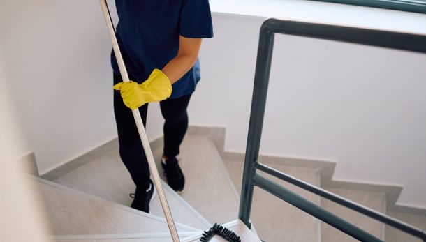 Happy maid mopping the stairs in a hallway. Copy space.